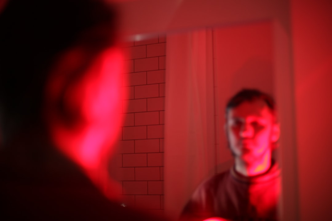 Banyo aynasında tıraş yapan birinin yüzü net şekilde görünür, sabah rutinini çağrıştırır