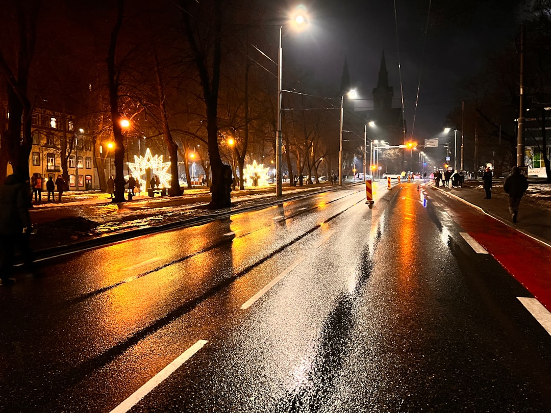 Islak kaldırım üzerinde yağmur altında yürüyen insanlar ve şehir manzarası