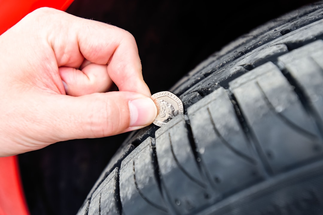 A person checking car tire pressure with a gauge