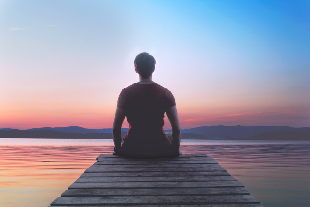 Bir kişi doğa içinde meditasyon yaparken sakinleşen yüz ifadesiyle görülüyor